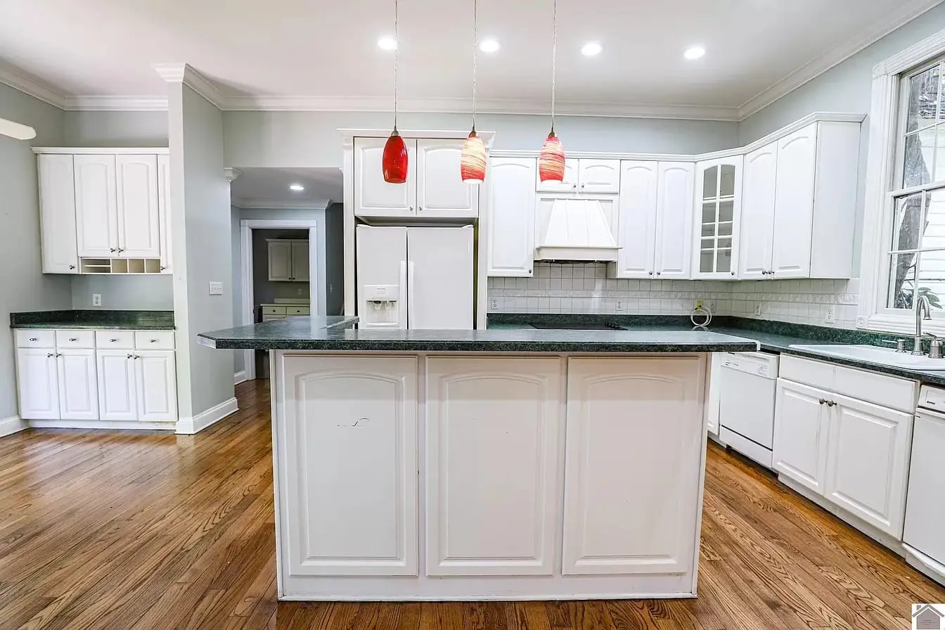 Before kitchen remodel: original white cabinets, green counters and red pendant lights